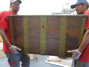 2 Guadeloupean men carrying a chest